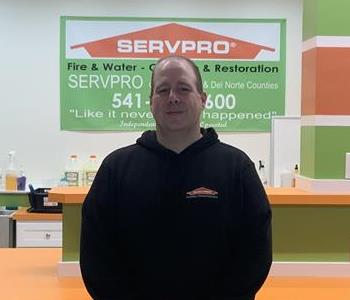 Photo of an employee with a black sweatshirt on standing in front of a SERVPRO counter.